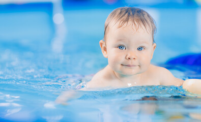 Portrait happy baby girl in swimming pool, teaching small swimmer. Concept healthcare sport for infant