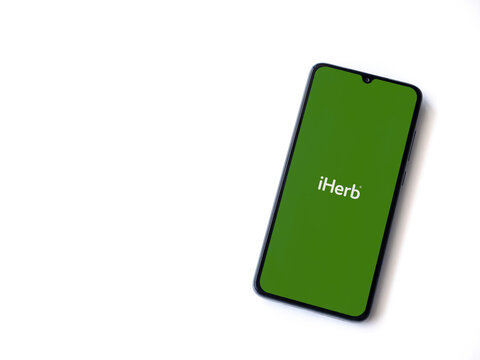 Lod, Israel - July 16,2023: iHerb app launch screen on smartphone on white background. Top view flat lay with copy space.