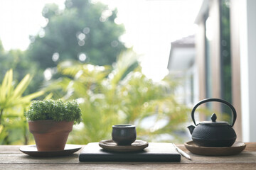Tea cup and metal teapot and plant pot on wooden table outdoor relaxing drinking