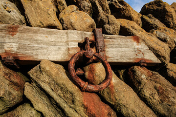 Rusty iron ring embedded in a harbor wall, used for mooring boats