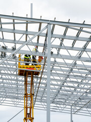 Fototapeta premium Complex large volume steel frame structure assembly using self propelled scissor lift platform