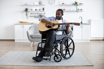 Cheerful smiling african person with disability holding string instrument in spacious apartment....