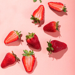 Fresh strawberries cut into slices on a pink background. Square crop, sunshine and shadows