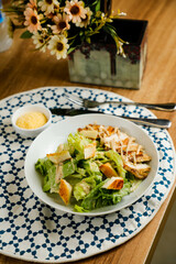 Caesar Salad or ceaser include chicken and spinach served in plate with flowers, knife and fork isolated on napkin side view of healthy green food on table