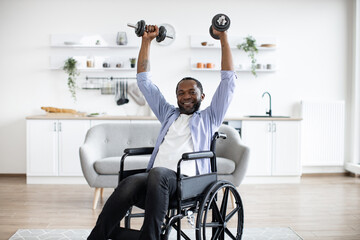 Delighted african male working out with dumbbell while staying in good mood on sunny day at home. Smiling mature person increasing endurance while doing exercise with disability.