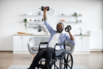 Close up view of handsome african man in wheelchair lifting weights while exercising with limited...