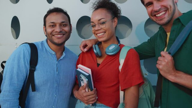 Cheerful multiracial students looking at camera and hugging outdoors 