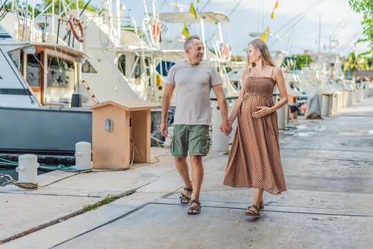A happy, mature couple over 40, enjoying a leisurely walk on the waterfront, their joy evident as they embrace the journey of pregnancy later in life