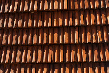 Orange texture of roof tiles in the rays of the setting sun.