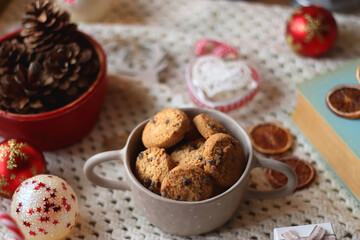 Various colorful Christmas decorations, soft blanket, cup of tea, sweet snacks and lit candles on the table. Cozy Christmas atmosphere at home. Selective focus.