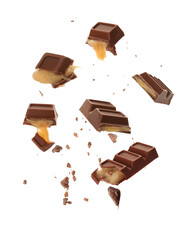 Pieces of delicious chocolate bars with caramel falling on white background