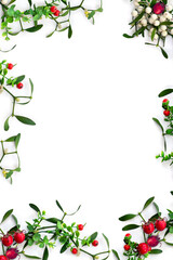 Christmas decoration. Branches with leaves and white berries mistletoe, red berries on a white background with space for text. Top view, flat lay
