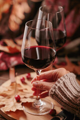 Autumn still life with two glasses of red wine and dry leaves in rustic style on dark wooden...