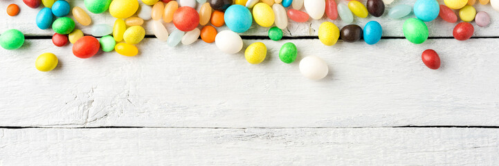 Various kinds of colourful sweets on white wooden table. Top view