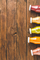Fresh fruit and vegetable juices in bottles on old wooden background with copyspace