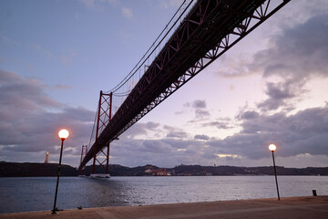 Beautiful landscape with suspension 25 April bridge bridge over the Tagus river in Lisbon at night time, Portugal.