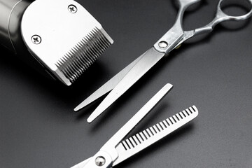 Barbershop concept. Hair clipper and Hairdresser scissors on black background top view space for text. Hair extensions, materials and cosmetics, hair care, wig. Hairstyle, haircut in salon.