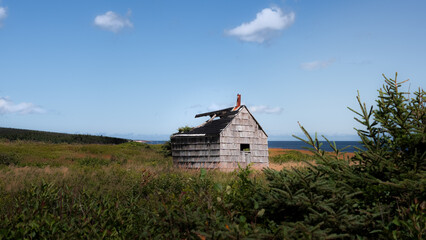 Photograph of a small house in the middle of fields by the sea. Roof torn off by a storm. 