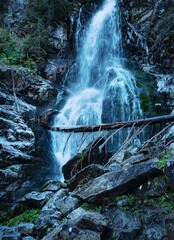 a tall waterfall cascading down around frozen rocks