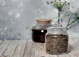 Dried seeds in a glass jar on the background of a teapot with tea on a natural wooden table. The...