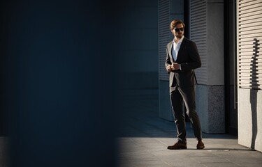 Fototapeta premium Elegant handsome man in classic suit standing near the office building.