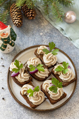 Creative appetizer christmas. Creamy pate sandwiches of herring on a rye bread on the festive table. Copy space.