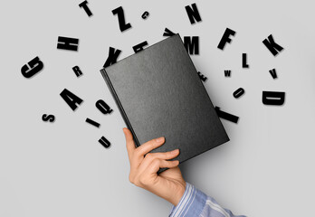 Hand with book and English letters on grey background