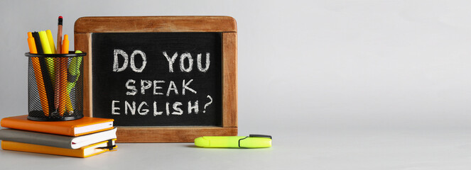 Stationery and chalkboard with text DO YOU SPEAK ENGLISH? on grey background with space for text - obrazy, fototapety, plakaty
