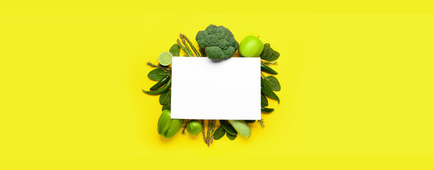 Different green vegetables, fruits and blank paper sheet on yellow background