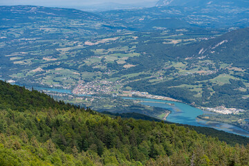 Naklejka na ściany i meble Grand Colombier, France - 08 31 2021: Grand Colombier Pass. View of the forest, the road, the Rhone river, the mountains ridge and Seyssel city behind.