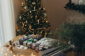 Wrapping christmas gifts. Stylish present, festive wrapping paper, ribbons, scissors, star and...