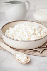 Bowl with tasty cottage cheese on light background