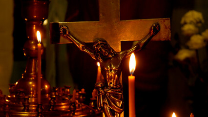 Church candles burn against the background of a cross depicting a crucifixion. Prayer and church...