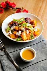 Roasted Vegetables, Feta Crumble and Citrus Salad served in bowl with flowers and fork isolated on napkin side view of healthy green food on table