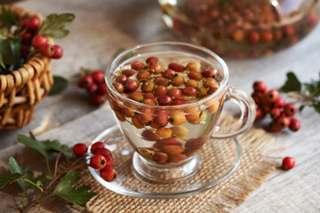 Hot herbal tea with fresh hawthorn berries in a glass cup