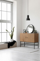 Interior of light hallway with mirror, wooden cabinet and big window