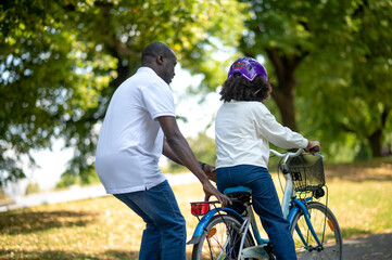 Father teaching his kids riding a bike and looking happy