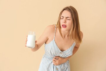 Young woman with lactose intolerance on  beige background - obrazy, fototapety, plakaty