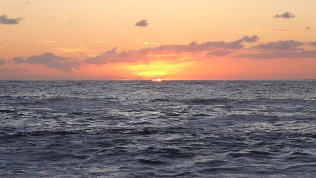 sun setting over the horizon of the sea, the real sound of the sea and the stunning picture of the waves rolling onto the shore