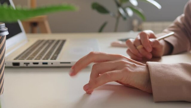 Unidentified female's hand nervously taping her desk with her fingers while working on her laptop in the office feeling stress while doing her job at workplace.