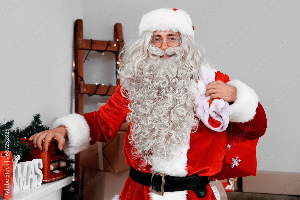 Poster Santa Claus holding bag of gifts in living room with Christmas decor