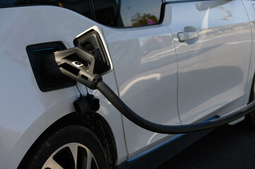 Close up on an electric vehicle, charging on a photovoltaic station at a roadside car park.
