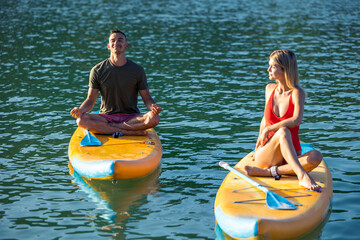 Woman man sup yoga, couple practicing yoga pilates on paddle sup surfboard.