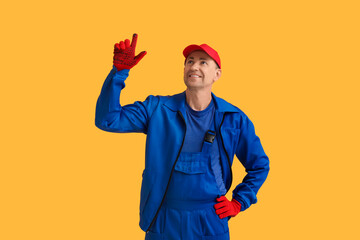 Portrait of male mechanic pointing up on orange background