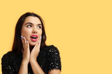 Beautiful young shocked woman on yellow background