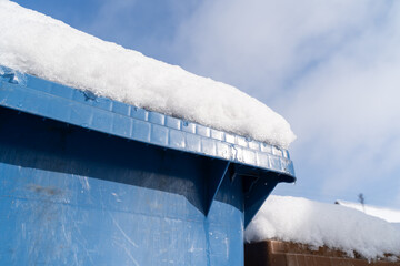 Blue garbage bin with snow in winter