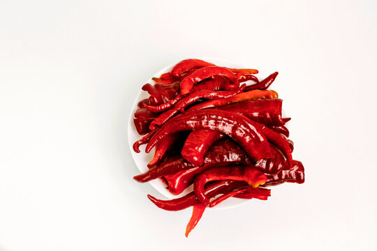 Sliced hot red pepper in a white plate on a white background.