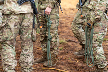 Multiple Army soldiers standing with rope in their hands.