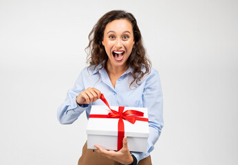 Glad millennial european woman in formal wear with open mouth open box with gift, screaming