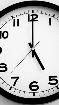 Closeup of White Clock Face on white wall clock, arrows show 17:00 or 05:00